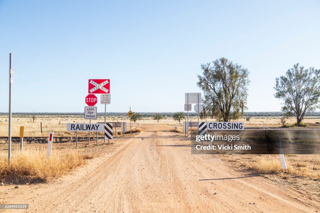 Dirt road going through a railway crossing in the dry, drought area of Australia