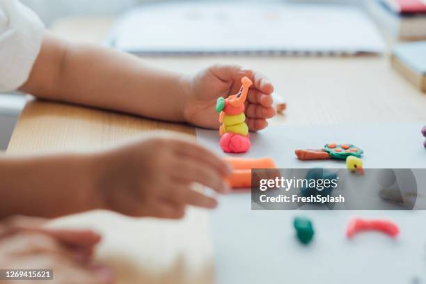 handen van een anoniem meisje dat plasticine beeldjes, kunst en ambachtsconcept maakt - klei stockfoto's en -beelden