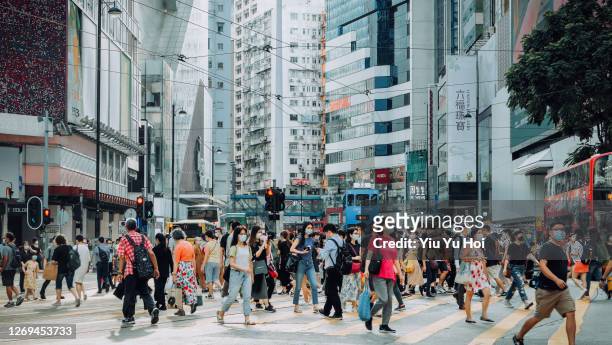 a typical city life in hong kong. crowd of busy commuters crossing the street in downtown district during rush hour against contemporary corporate skyscrapers and city traffic - hong kong street 個照片及圖片檔
