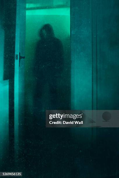 a halloween concept of a blurred scary, hooded figure, standing in a doorway. with a dusty, vintage, abstract edit. - magic doors stock pictures, royalty-free photos & images