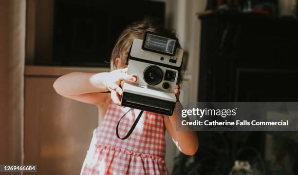 girl taking an image with an instant camera - nachahmung erwachsener stock-fotos und bilder