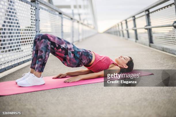 young sporty woman practicing yoga, doing dvi pada pithasana exercise, glute bridge pose, working out, wearing sportswear, outdoors - women buttocks stock pictures, royalty-free photos & images