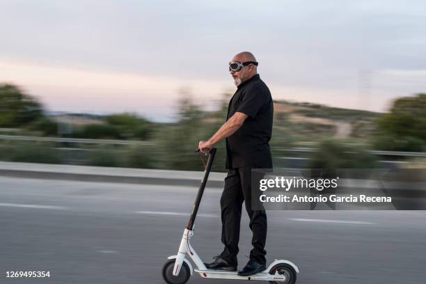 sweep photo of mature man driving an electric scooter, sweeping effect for green vehicle promotion - roller skate stock-fotos und bilder