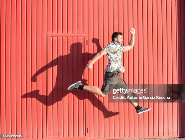 40-year-old man jumps on red background with happy summer clothes - 40 year old man stockfoto's en -beelden