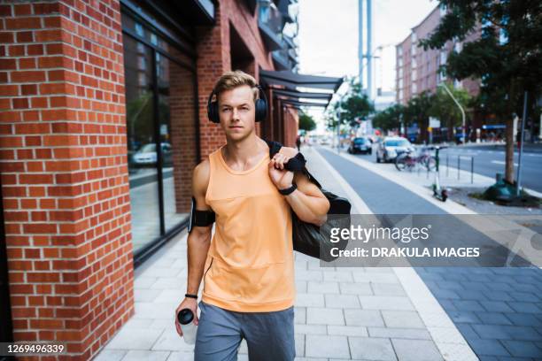 young man with a gym bag in a city - gym bag fotografías e imágenes de stock