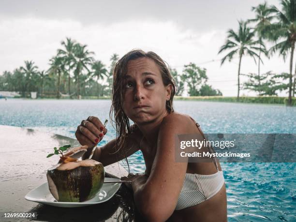 woman at the pool-bar annoyed by the torrential rain - holiday sadness stock pictures, royalty-free photos & images