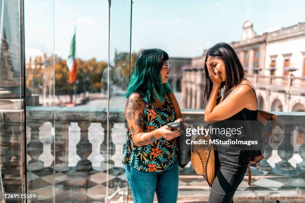 two young women looking at the mobile phone - three quarter length stock pictures, royalty-free photos & images