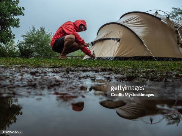 mens die in een regenbui wordt gevangen terwijl het kamperen - camp tent stockfoto's en -beelden