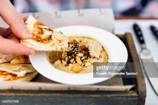 close-up of man eating hummus with pita bread - dip stockfoto's en -beelden