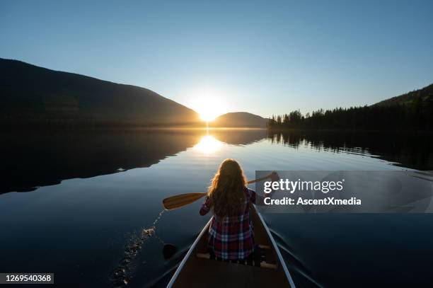 woman canoeing on a stunning mountain lake - green boat stock pictures, royalty-free photos & images