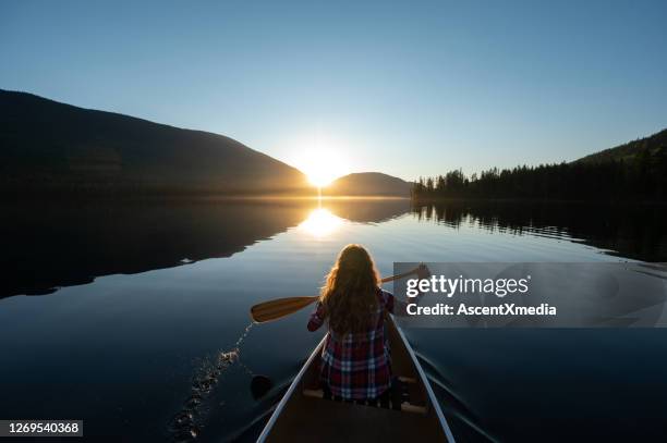 woman canoeing on a stunning mountain lake - sunset rays stock pictures, royalty-free photos & images