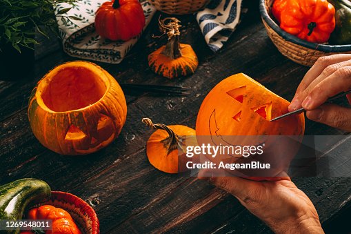 Man Carving Spooky Face on a Pumpkin For Halloween Man Carving Spooky Face on a Pumpkin For Halloween