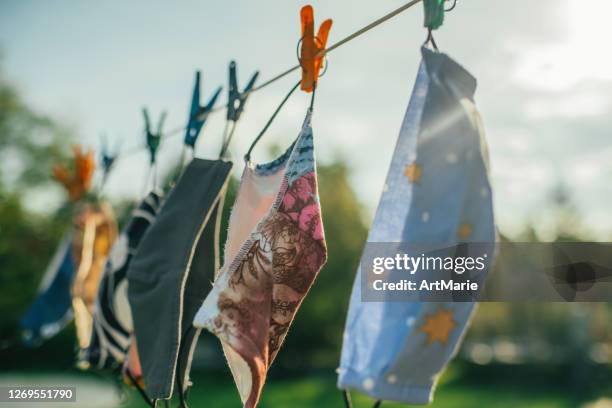 reusable fabric protective face masks hanging outdoors and drying in a sunny day - cloth face mask stock pictures, royalty-free photos & images