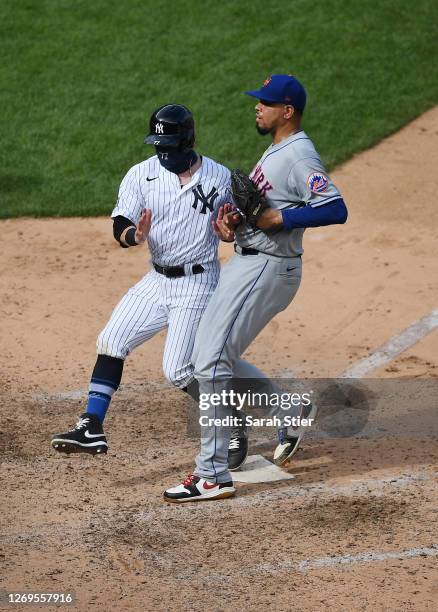 Clint Frazier of the New York Yankees collides with Dellin Betances of the New York Mets as he crosses home plate to score on Betances' wild pitch...