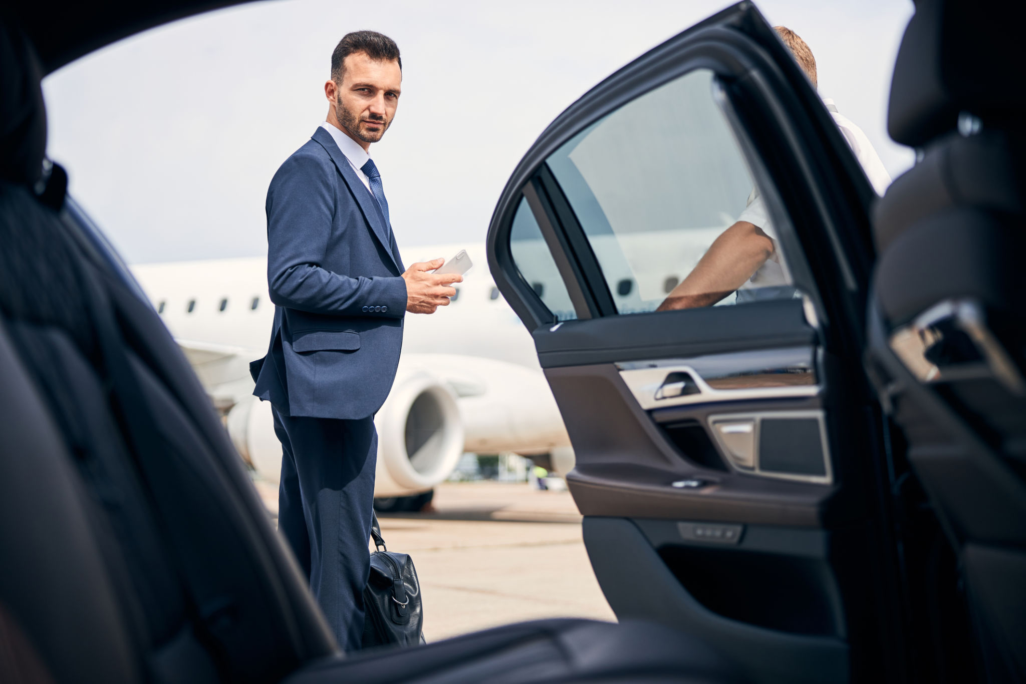 Successful businessman standing by the car looking determined Successful businessman standing by the car looking determined