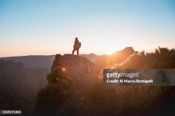 one woman standing on top of a mountain at sunset, madeira - pico do arieiro fotografías e imágenes de stock