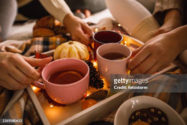 unkenntlich zuerkennende junge frauen genießen warmen tee an einem kalten herbsttag - hot beverage stock-fotos und bilder