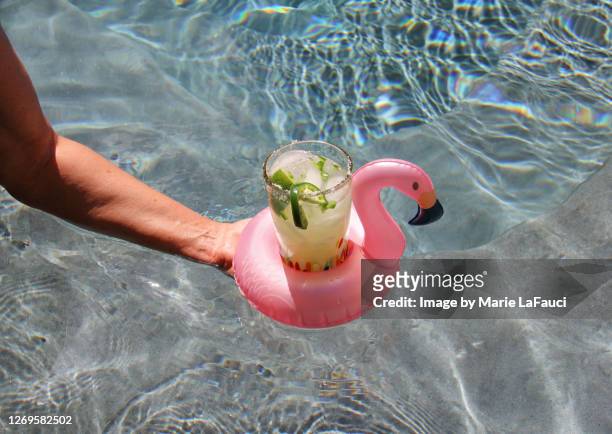 serving a drink at the pool in a pink flamingo float - alcohol top view stock-fotos und bilder