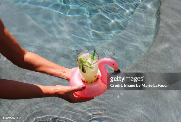 swimming pool with drink served in a pink flamingo float coaster - flamingos stock-fotos und bilder