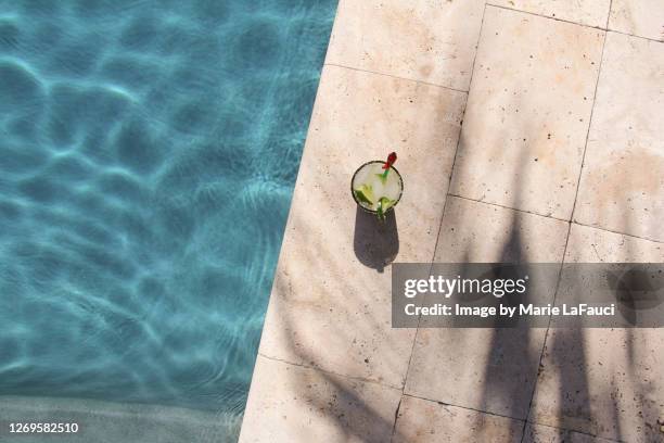 top angle view of a cocktail on the edge of a swimming pool - cocktail party stockfoto's en -beelden