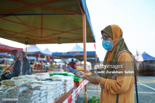 muslim woman in hijab wearing mask at pasar tani or farmer's market in kuala lumpur - malaysian ringgit stock pictures, royalty-free photos & images