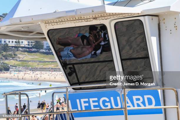 Beachgoers reflected in the lifeguard tower at Bondi Beach on August 30, 2020 in Sydney, Australia. Warm winter weather is being enjoyed across the...