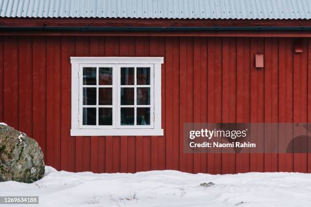 red rorbuer (fishermen's cabin) with a white framed window, surrounded by snow - lofoten islands, norway - cabin norway stock pictures, royalty-free photos & images