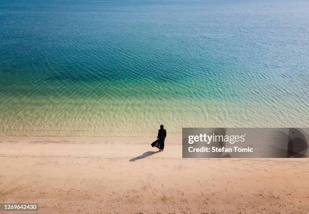 muslim woman wearing hijab abaya dress on the beach aerial view - muslim woman beach stock pictures, royalty-free photos & images