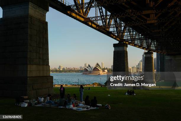 People enjoy picnics underneath the Harbour Bridge approach spans during the sunset in the suburb of Kiribilli on August 30, 2020 in Sydney,...