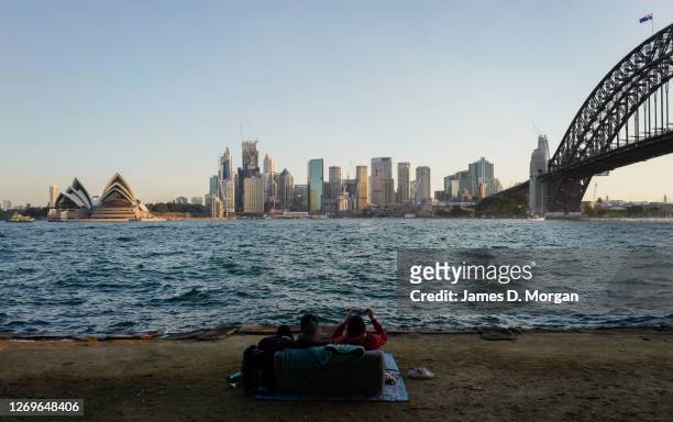 Man and woman sit on a sofa to enjoy the sunset in the suburb of Kiribilli on August 30, 2020 in Sydney, Australia. Warm winter weather is being...