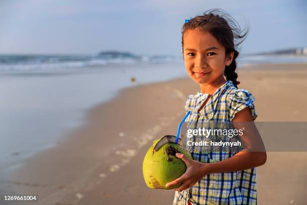 vietnamesisches mädchen halten kokosnuss am strand, vietnam - vietnamesischer abstammung stock-fotos und bilder