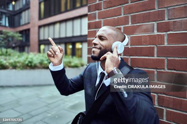 a joyful businessman enjoys music after a hard day - city break stock-fotos und bilder