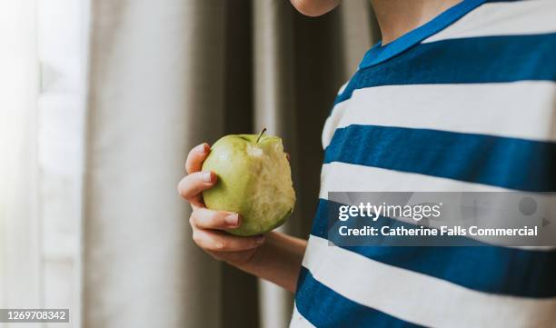 boy holding a half-eaten green apple - child holding apples stock-fotos und bilder