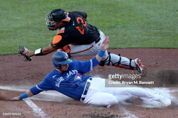 Pedro Severino of the Baltimore Orioles attempts to tag Joe Panik of the Toronto Blue Jays during the fifth inning at Sahlen Field on August 30, 2020...