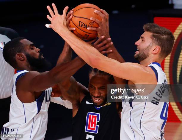 Kawhi Leonard of the LA Clippers drives between Tim Hardaway Jr. #11 and Maxi Kleber of the Dallas Mavericks during the third quarter in Game Six of...