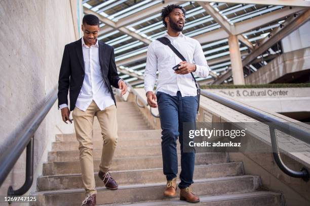 two black business partners walking together in the city - walking street friends stock pictures, royalty-free photos & images