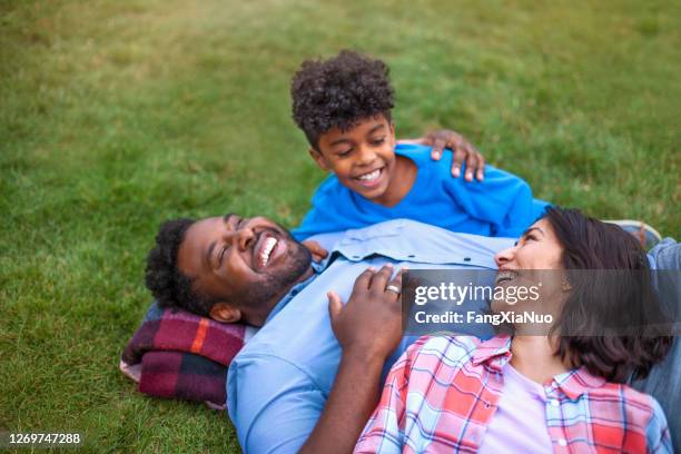 multikulturelle gemischte rasse multiethnische familie mit einem kind auf gras lachen - mixed race family stock-fotos und bilder