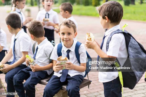 junge schüler essen nach der schule im park. - girls laughing eating sandwich stock-fotos und bilder