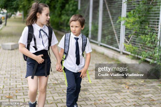 学校に行く途中で通りを歩く兄弟姉妹 - 子供のみ ストックフォトと画像