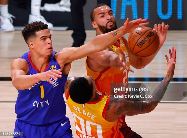 Rudy Gobert and Jordan Clarkson of the Utah Jazz reach for a loose ball against Michael Porter Jr. #1 of the Denver Nuggets during the second quarter...