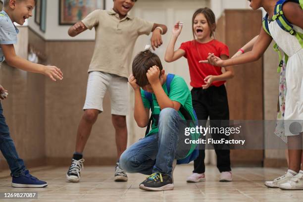 kinderen houden zich bezig met pestgedrag jegens een schooljongen - bully stockfoto's en -beelden