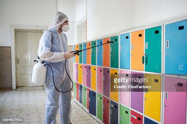 sanitation worker disinfect with anticeptic a kids lockers in a school hall - disinfection school stock pictures, royalty-free photos & images