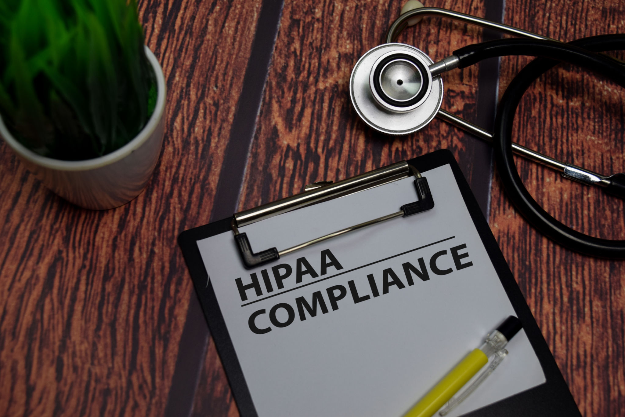 HIPAA Compliance write on paperwork isolated on wooden table. HIPAA Compliance write on paperwork isolated on wooden table.
