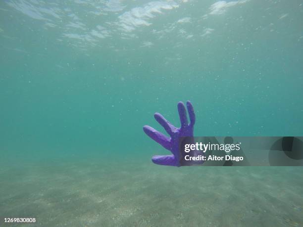 rubber glove floating in the water of the sea. almería, spain. - 海 汚染 ストックフォトと画像