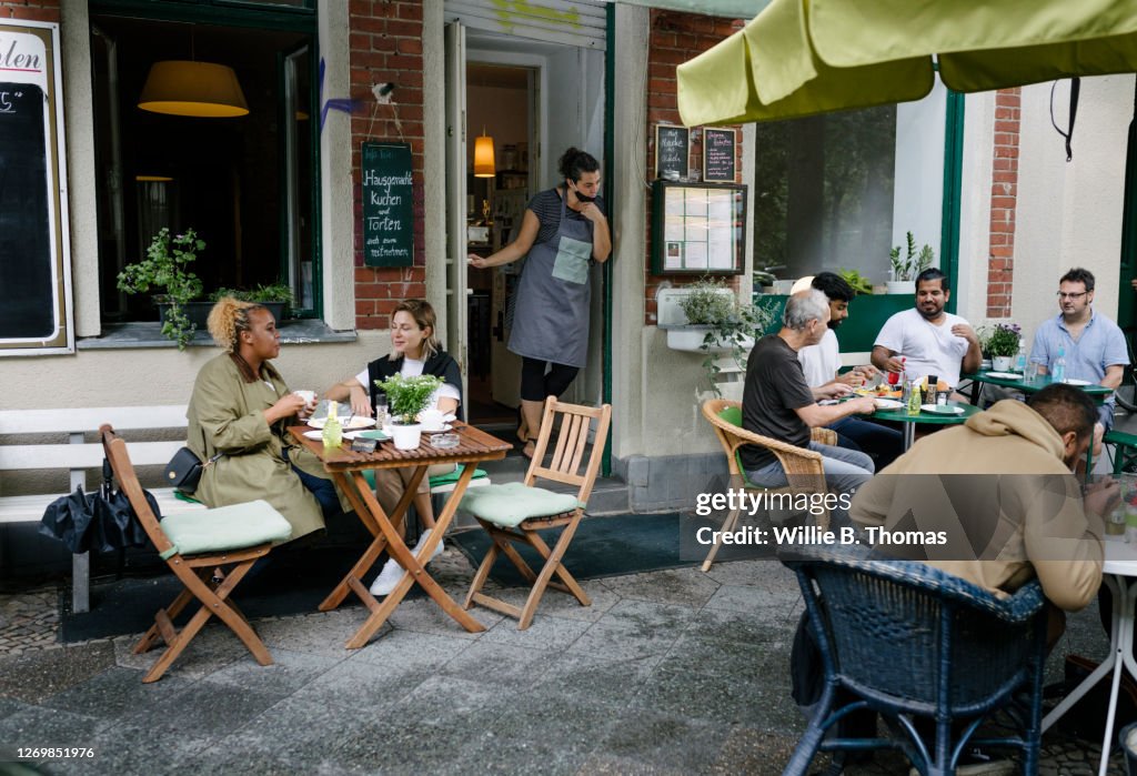 Busy Restaurant Facade With People Sitting And Eating