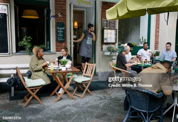 busy restaurant facade with people sitting and eating - café esplanada imagens e fotografias de stock