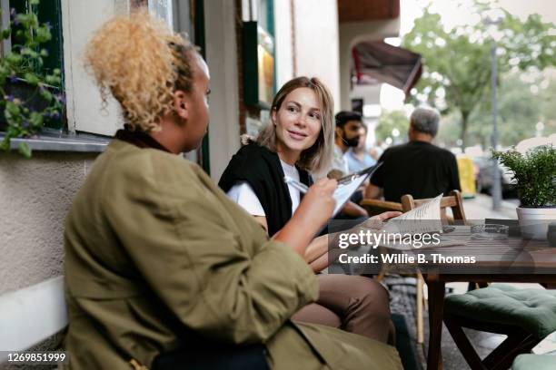 friends chatting outside restaurant - 2 frauen gespräch ohne männer cafe stock-fotos und bilder