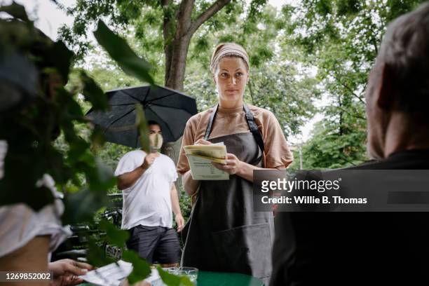 waitress working outdoors at restaurant on rainy day - waitress foto e immagini stock