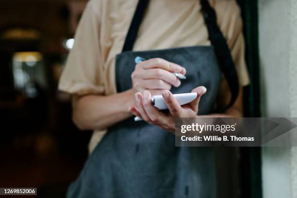 waitress writing on notepad - kellner oder kellnerin stock-fotos und bilder