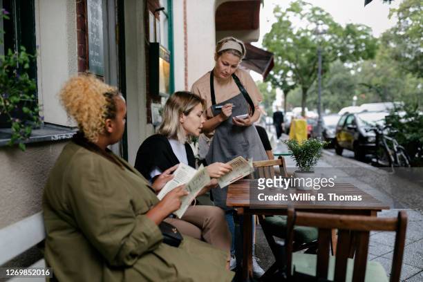 waitress taking order from customers sitting outside restaurant - service on demand stock-fotos und bilder